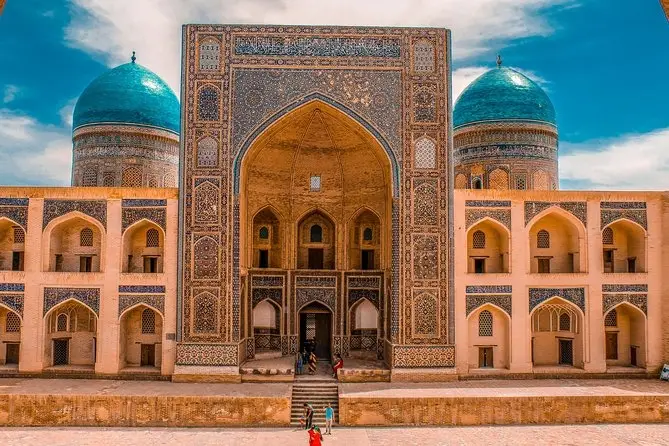 Arched facade and twin blue domes of a Bukhara madrasah