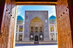 A carved wooden door opening onto a tiled madrasah courtyard